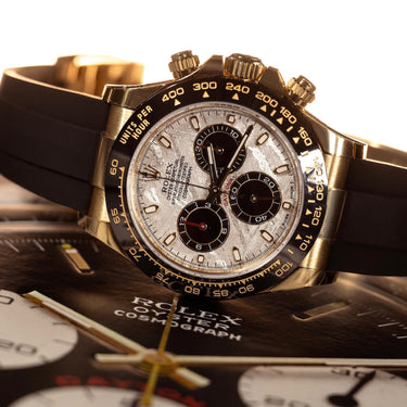 Gold Rolex Daytona with meteorite dial, laid sideways with photographic background.